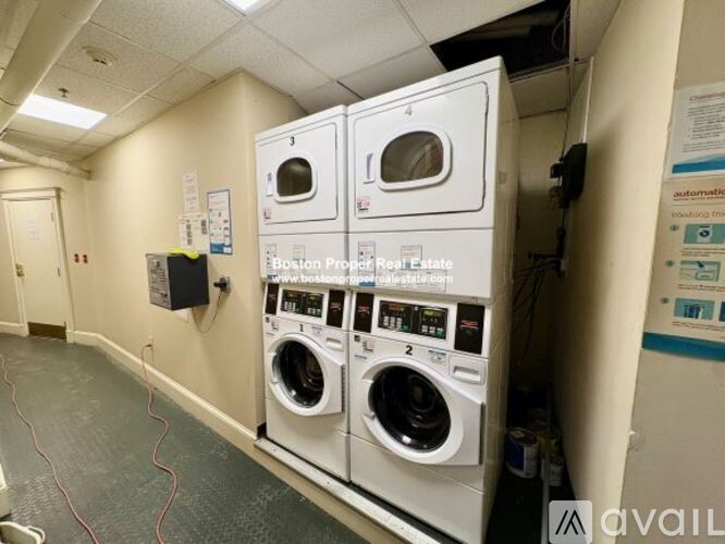 A row of white washing machines are stacked on top of each other in a laundry room.