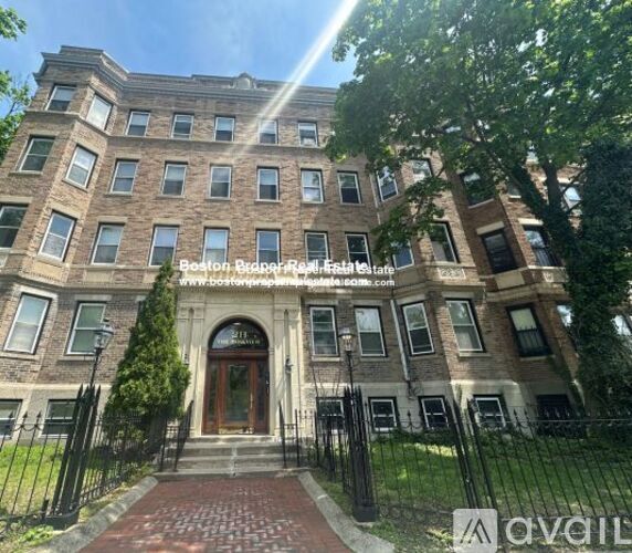 A large, multi-story building with a brick facade and a black iron fence in front.