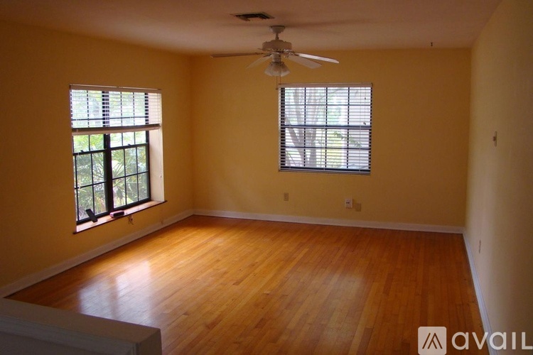 A room with wooden floors and two windows.