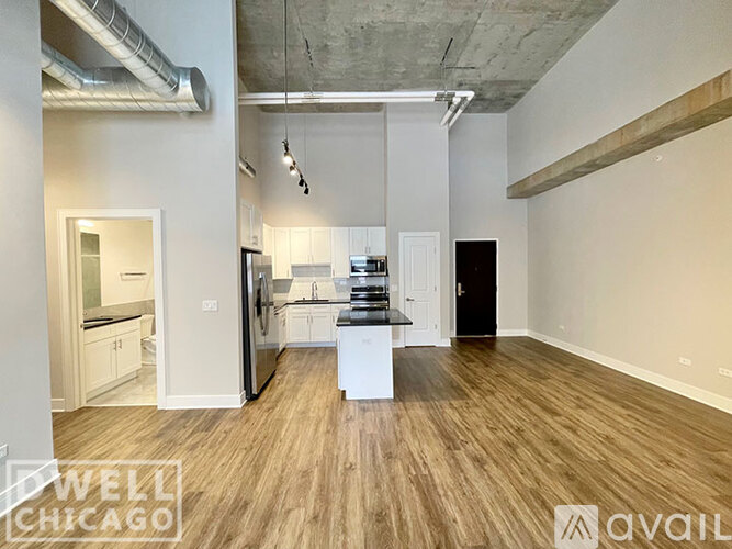 A spacious kitchen with white cabinets and a black fridge is available for rent.