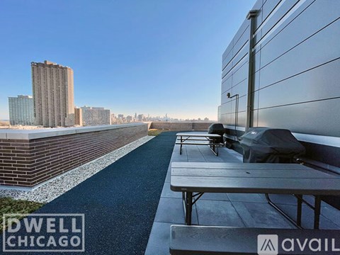 A long concrete bench with a black bag on it is in front of a building.