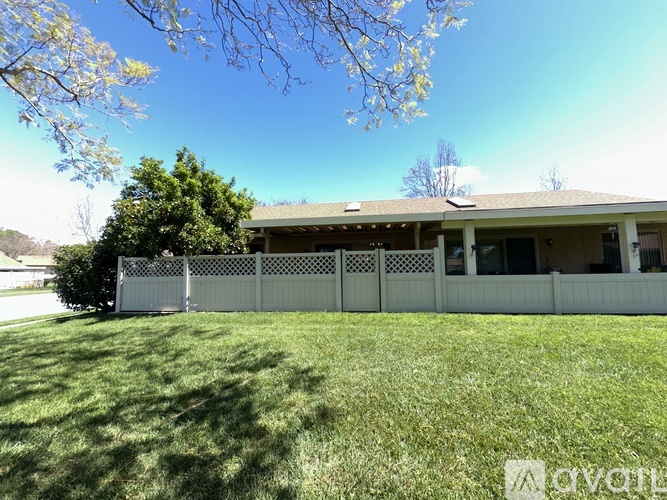 A house with a white fence and green lawn.
