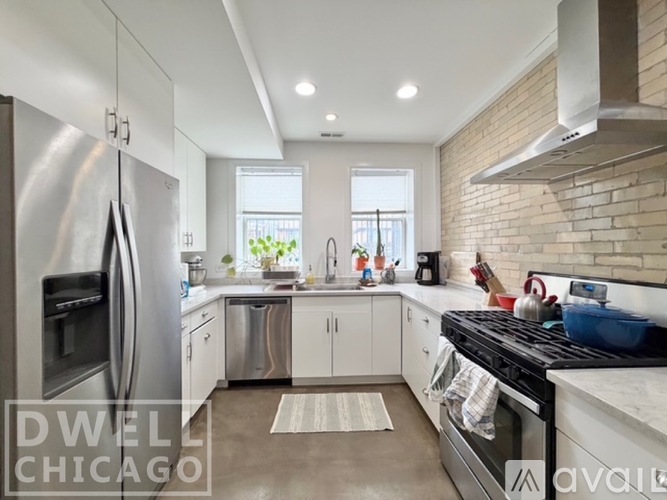 A modern kitchen with a stainless steel refrigerator and a black stove top.