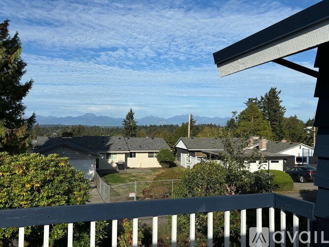 A view from a balcony overlooking a residential area with houses and mountains in the distance.