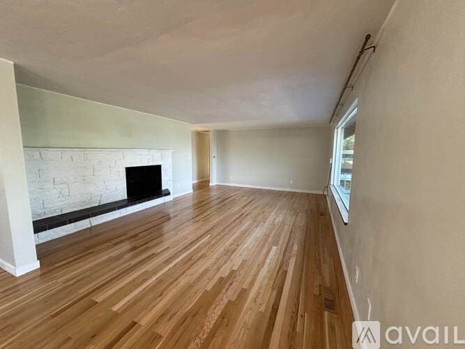 A room with wooden flooring and a fireplace.