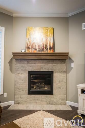 A fireplace with a painting above it and a rug in front.