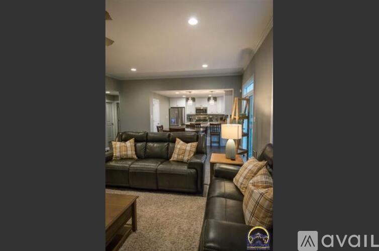 A living room with a black leather couch and a wooden coffee table.