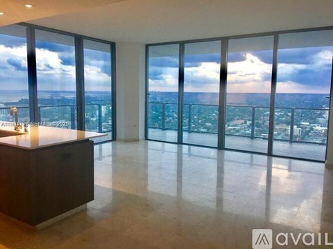 A spacious room with a view of the cityscape through large windows.