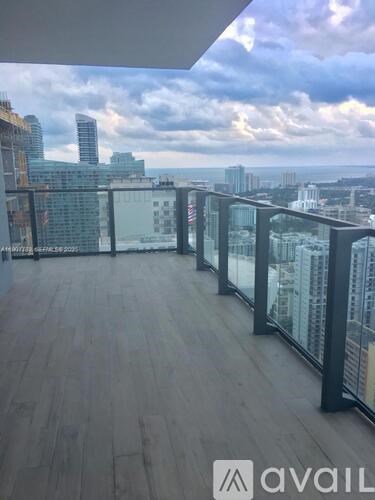 A balcony with wooden flooring and glass railings overlooking a cityscape.