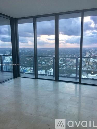 A large empty room with a view of the cityscape outside the windows.