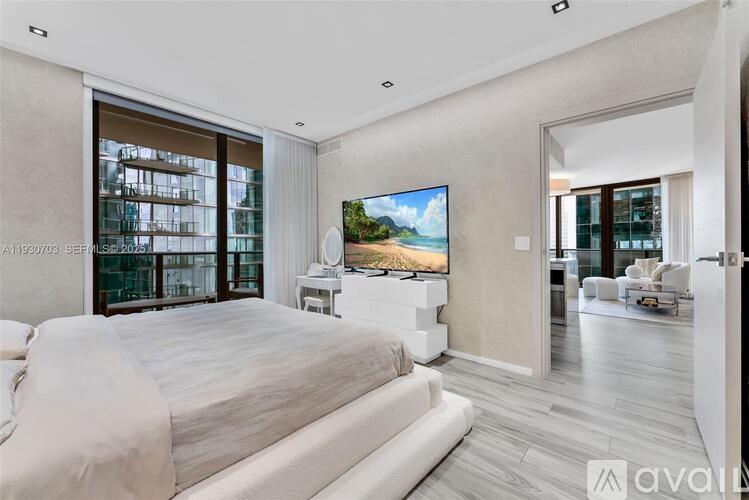 A bedroom with a large bed and a flat screen TV mounted on the wall.