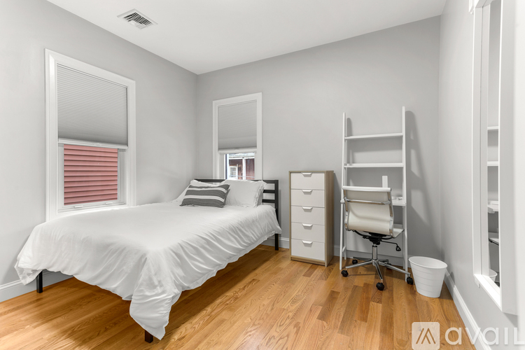 A bedroom with a bed, a chair, and a cabinet.