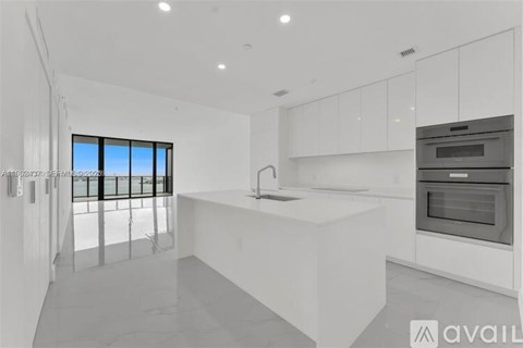 A modern kitchen with white cabinets and a large island.
