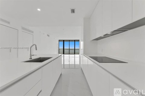 A modern kitchen with white cabinets and a large window.
