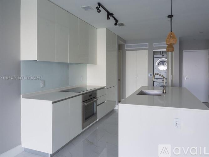 A modern kitchen with white cabinets and stainless steel appliances.