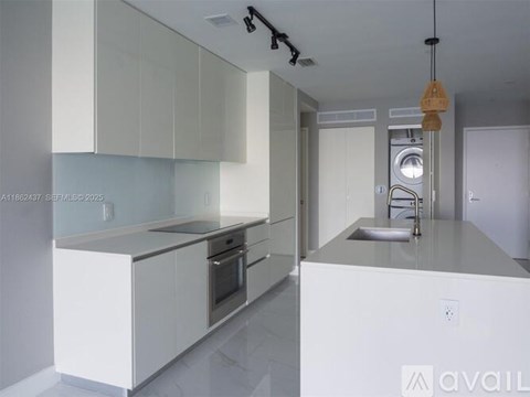 A modern kitchen with white cabinets and stainless steel appliances.