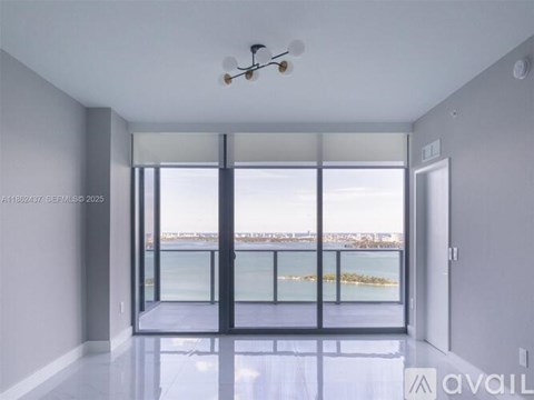 A spacious room with a ceiling fan and a view of the water.