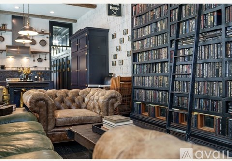 A room with a brown leather sofa and a bookshelf filled with books.