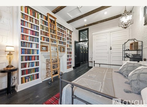 A bedroom with a large bed, a bookshelf filled with books, and a chandelier hanging from the ceiling.