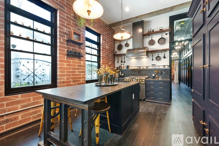 A kitchen with a brick wall and a table with chairs.