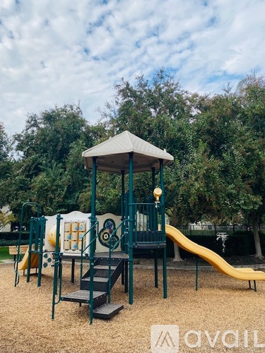 A playground with a yellow slide and a green structure.