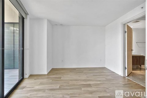 A spacious room with wooden flooring and white walls.