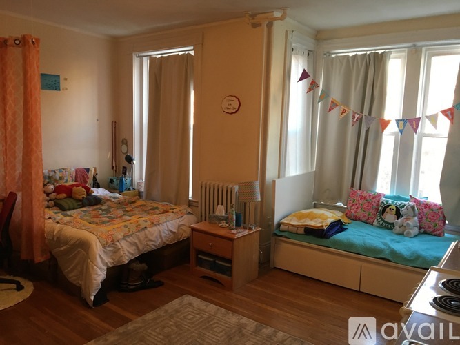 A bedroom with a bed, a bedside table, and a window with curtains.