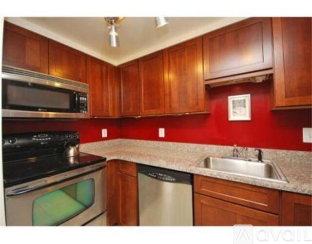 A kitchen with wooden cabinets and a red wall.