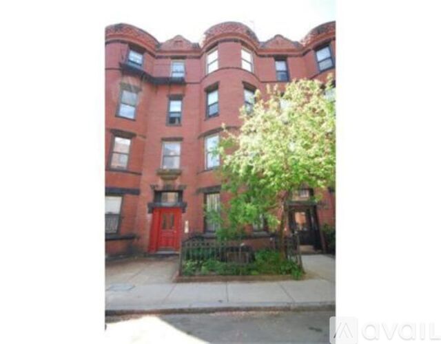 A red brick building with a tree in front.