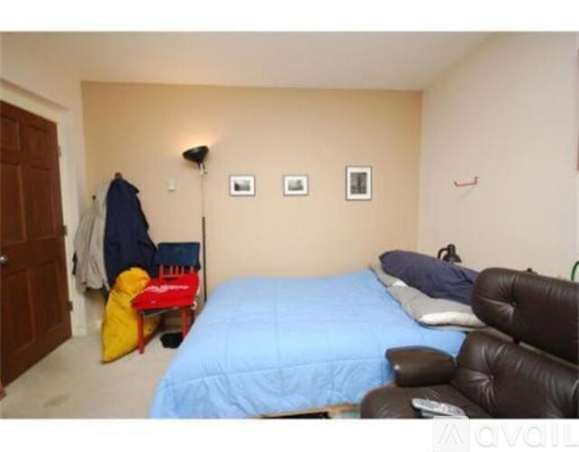 A bedroom with a blue bed and a brown leather chair.