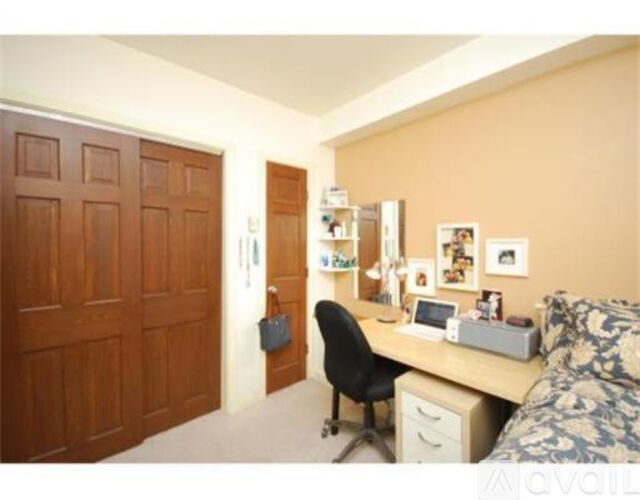 A room with a desk, chair, and a bed.