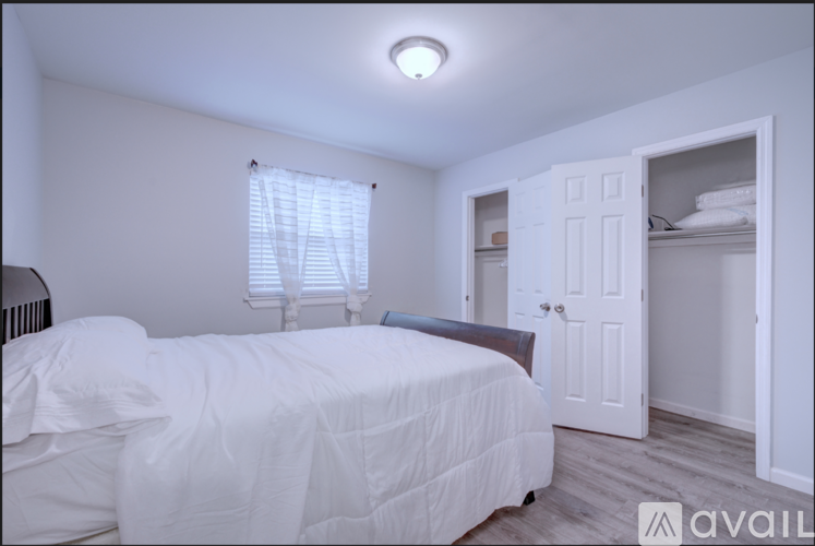 A bedroom with a white bed and a white wardrobe.