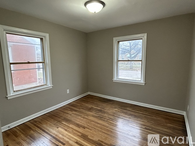 A room with wooden floors and two windows.
