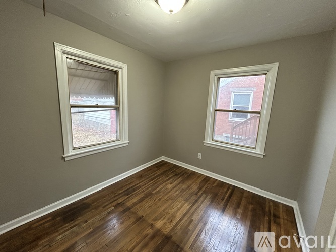 A room with wooden floors and two windows.