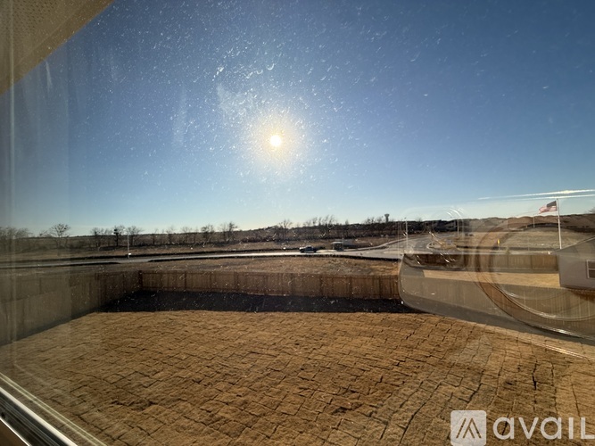 A view from a window looking out to a brick patio and a clear blue sky.