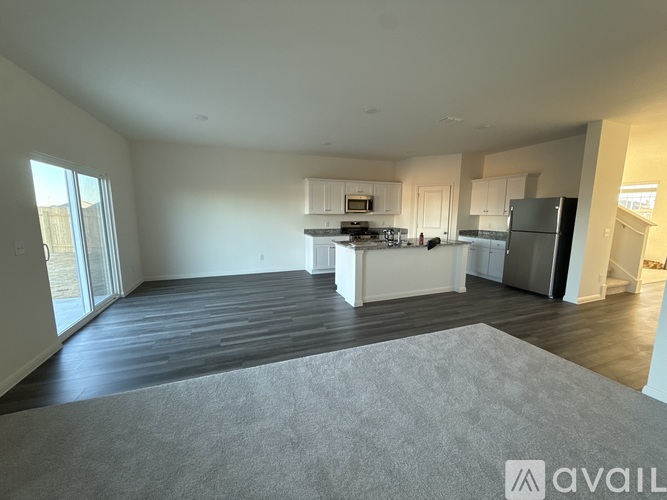 A spacious kitchen and living room with a grey rug on the floor.