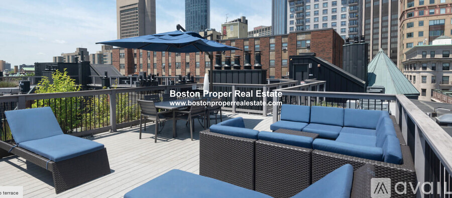 A rooftop patio with blue furniture and a city skyline in the background.