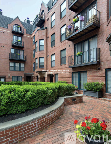 A brick building with balconies and a garden in front.