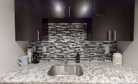 A modern kitchen with a stone backsplash and a marble countertop.