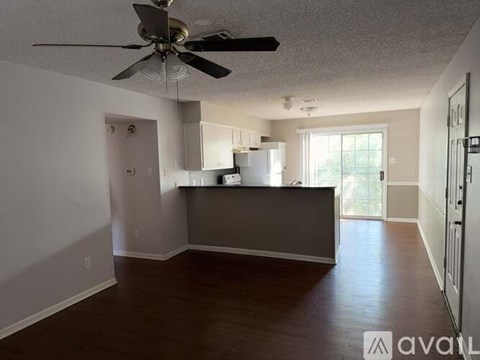 A room with a ceiling fan and a kitchenette.