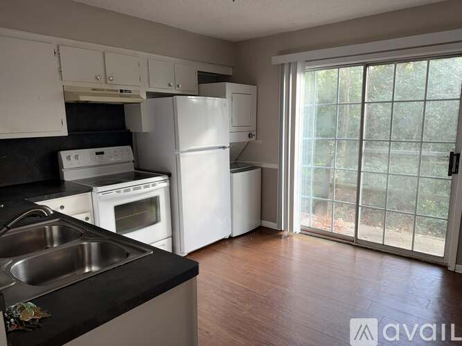 A kitchen with white appliances and black countertops.