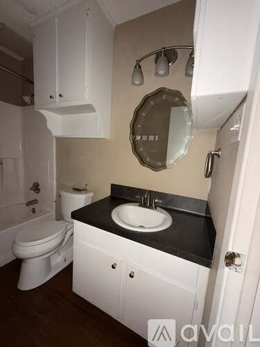 A bathroom with a toilet, sink, and mirror.