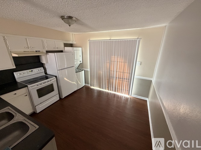 A kitchen with white appliances and wooden floors.