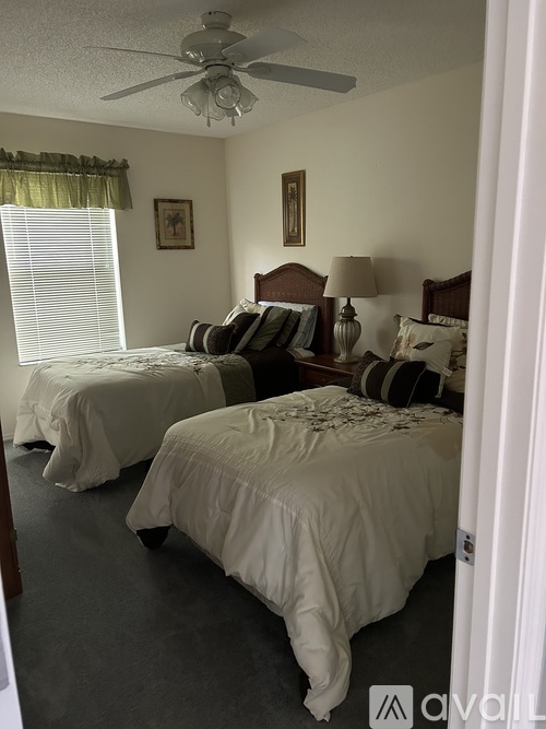 A bedroom with two beds and a ceiling fan.