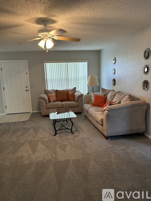 A living room with a beige carpet and two couches.