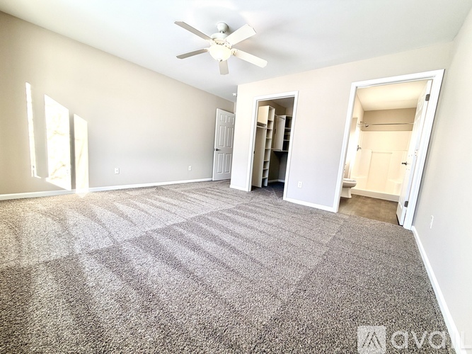 A room with a carpeted floor and a ceiling fan.