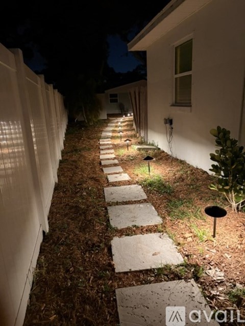 A garden pathway is illuminated by lights at night.