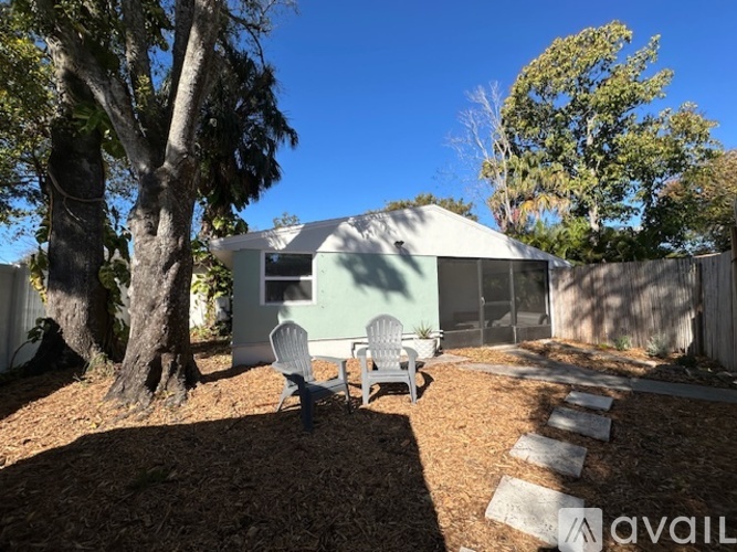 A backyard with a tree, a chair and a house.