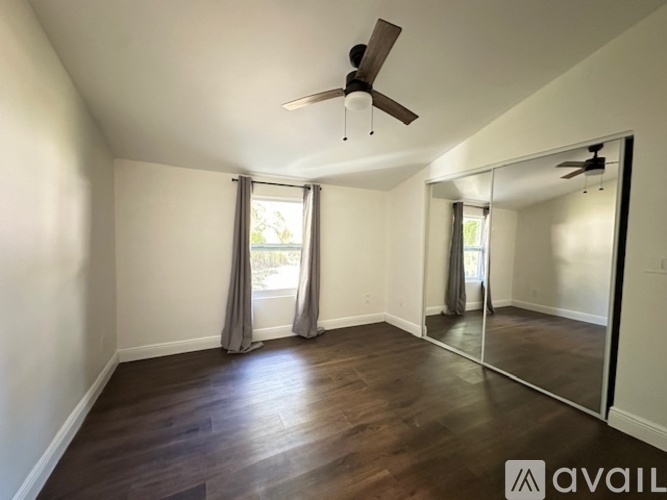 A spacious room with a ceiling fan and a large mirror on the wall.