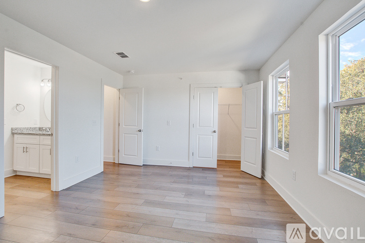 A spacious room with wooden flooring and white walls.